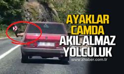 Ayaklarını camdan sarkıtarak trafiği tehlikeye attı
